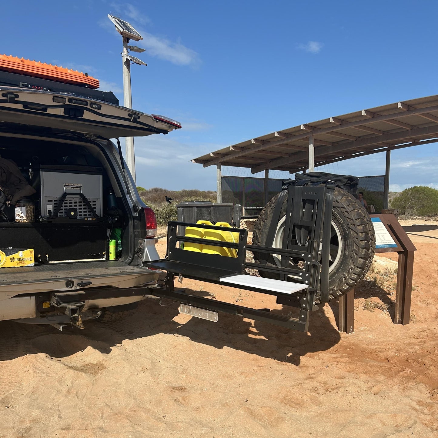 Suv with open cargo area and large tire display on a dirt road