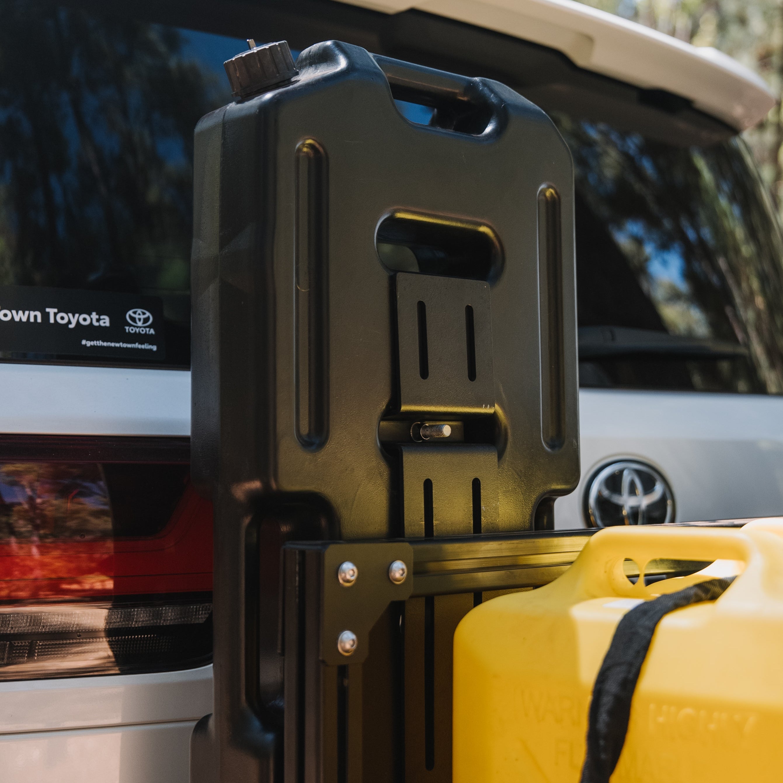 Black fuel tank holder attached to a Toyota vehicle with a yellow fuel tank.