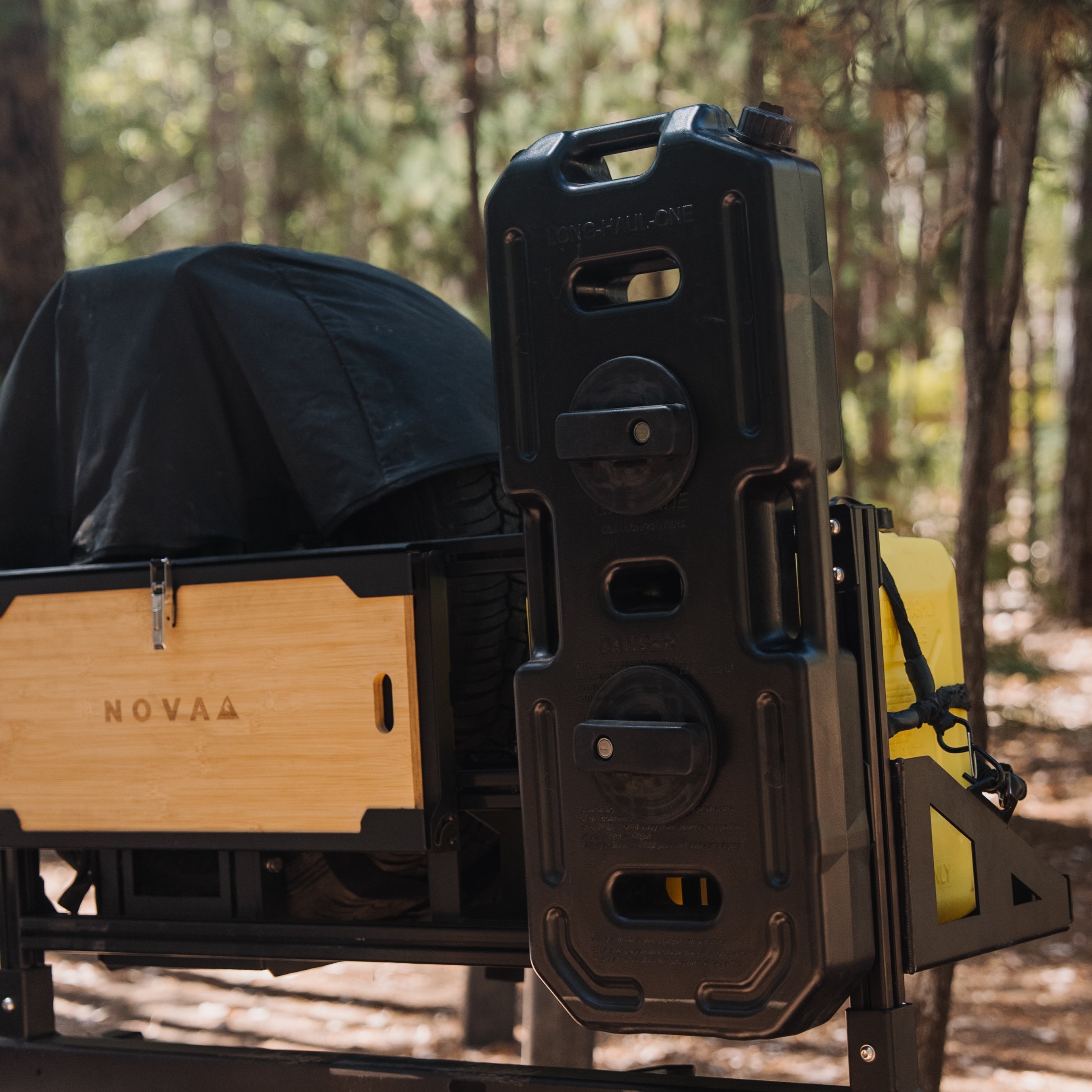 Back of a truck with a wooden storage box and black equipment case in a forest setting