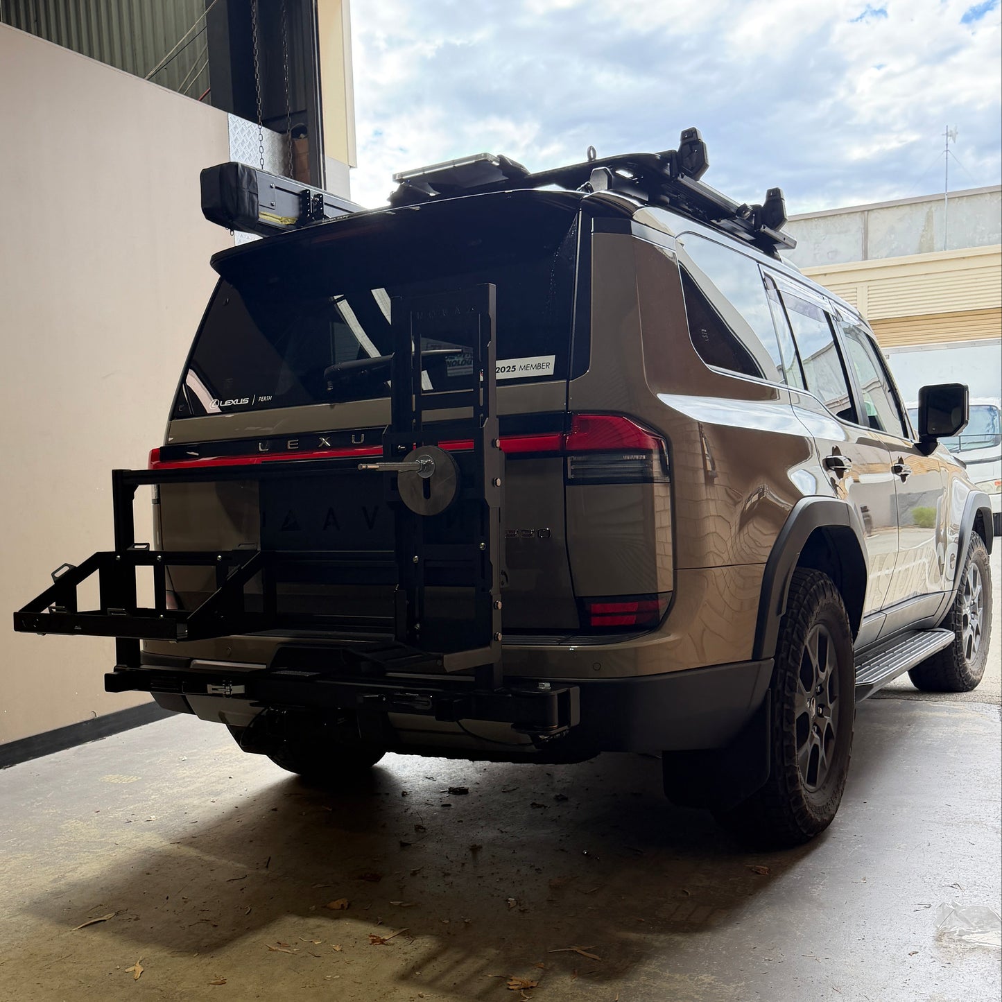 Car with a roof rack parked on a concrete surface near a building.