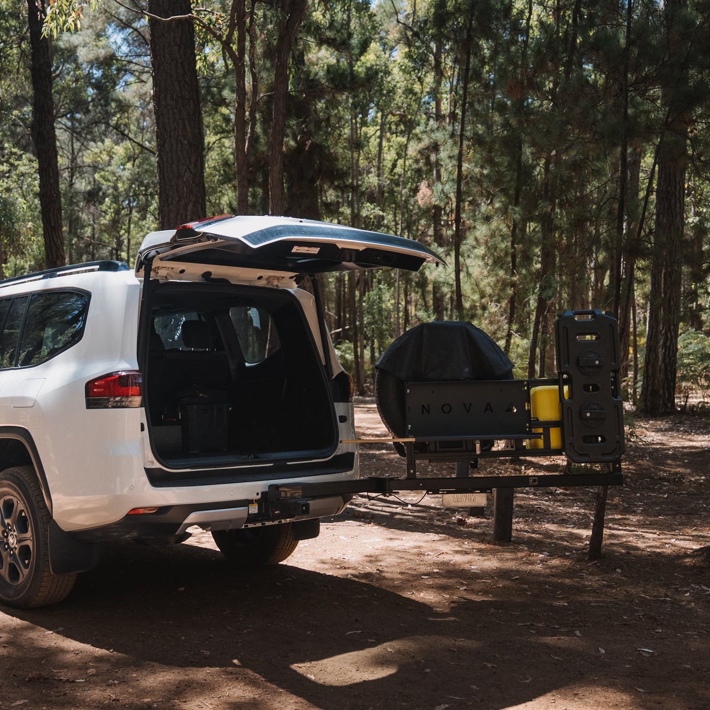 White SUV with an open trunk in a forest setting