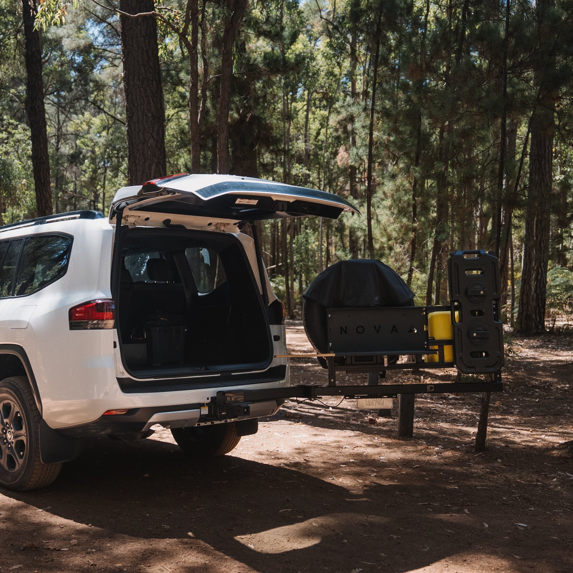 White SUV with an open trunk in a forest setting