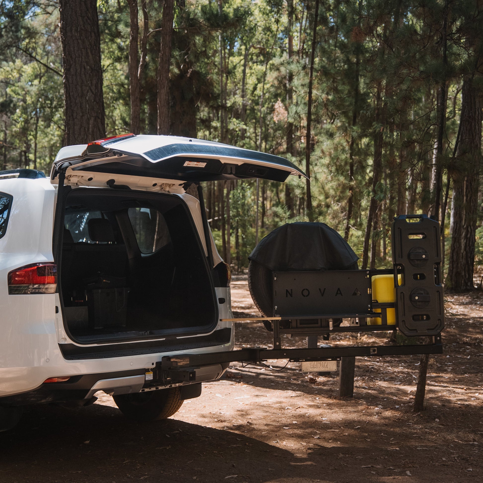 White SUV with an open cargo area in a forest setting