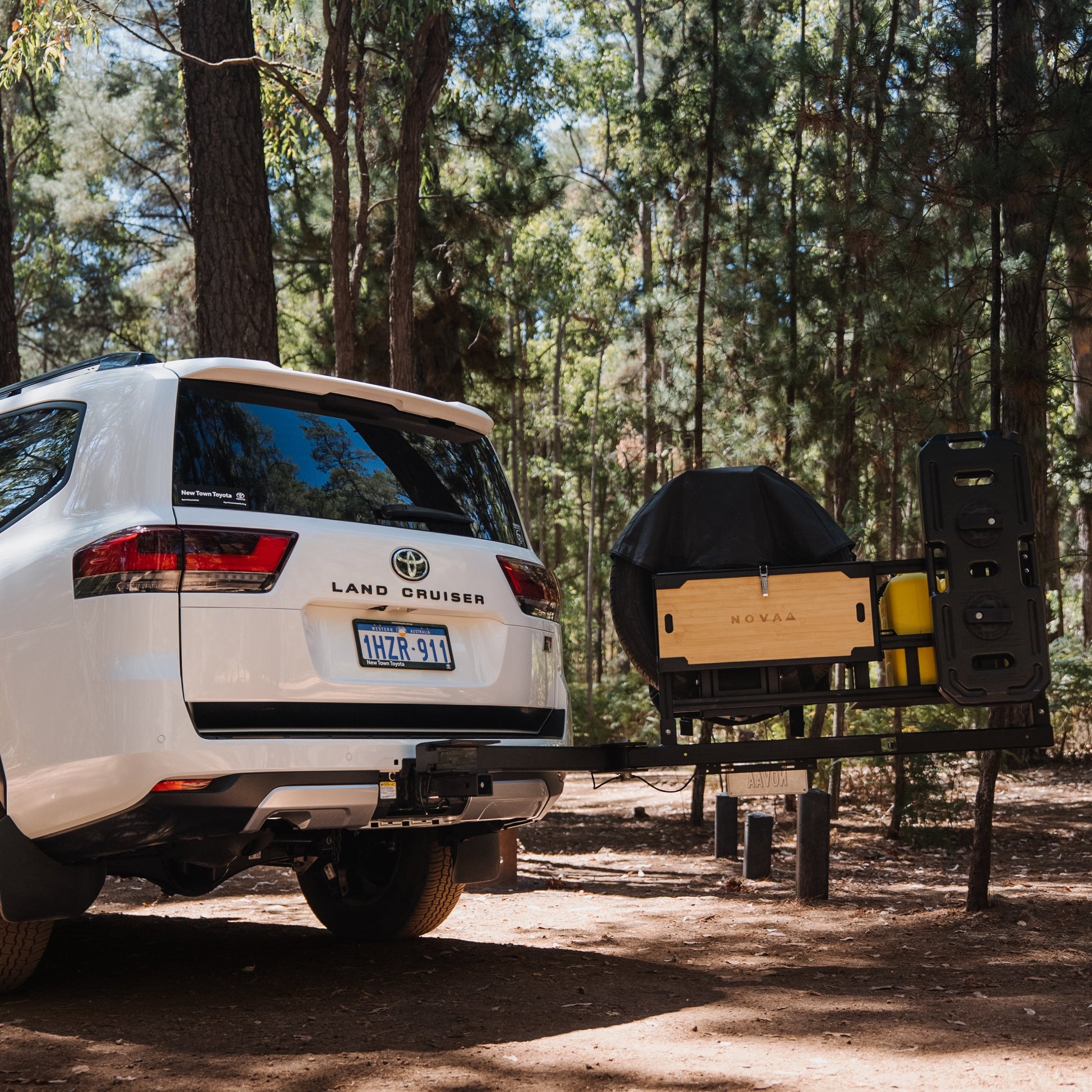 White Land Cruiser vehicle with a trailer attached in a forest setting